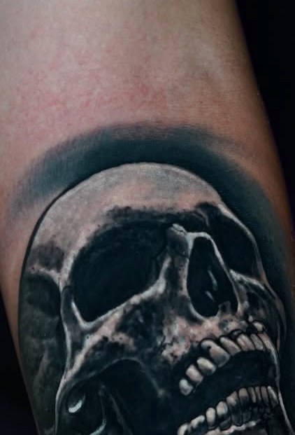 Black and grey skull tattoo on a forearm