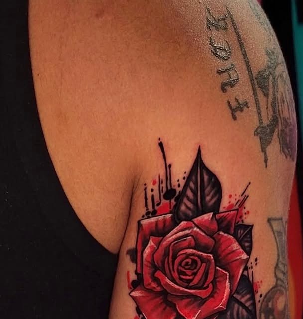 Red rose tattoo with black leaves on a shoulder